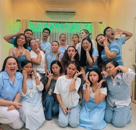 A group of men and women wearing blue and white and striking a silly pose