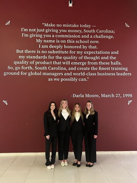 Students in business attire posing with quote on wall in Spain