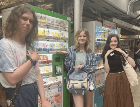students posing in front of japanese vending machines