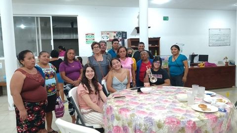 Students sitting at a table while the community stands behind them