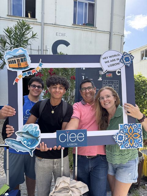 Students posing with their host family in a CIEE picture frame