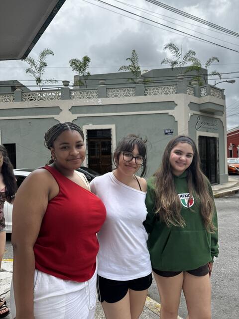 3 students wearing red, white, and green stand in Merida historic city center