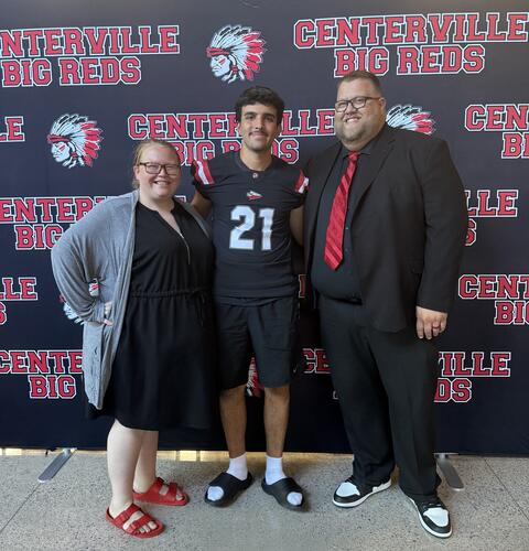 Shannon and Jarred Johnston pose with exchange student Cem after a football game.