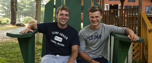 Two summer camp counselors sitting on big green chair