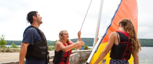 Counselors and kid setting up a sail boat