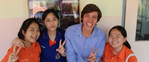 Teach Abroad Teacher and students smiling together against wall