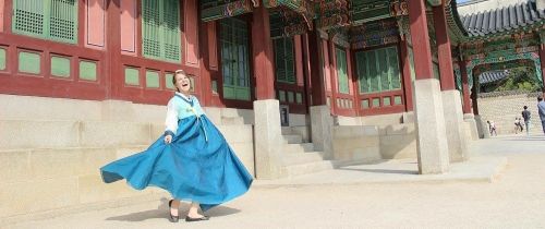 Teacher in traditional Korea dress smiling in front of a temple