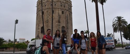 High school students in front of tower and palm trees in Seville