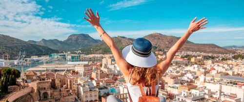 spain woman in murica sitting above city with her hands up