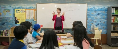 TEFL teacher holding up hands in front of class