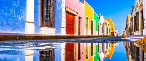 colorful buildings in yucatan mexico reflected in a puddle of water