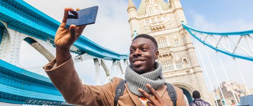 man-taking-selfie-london-tower-bridge-in-background