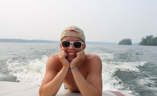 Counselor smiling on a wakeboard on the water