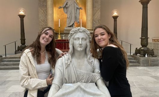 High school girls posing with a statue in a cathedral