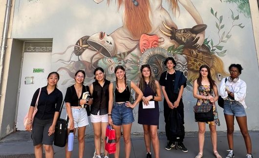 High school summer students standing in front of a mural