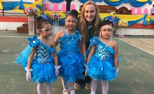 Young female teacher with Thai students in costumes at festival