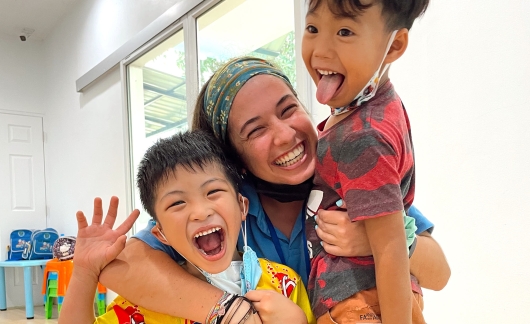 Teacher and students smiling and hugging