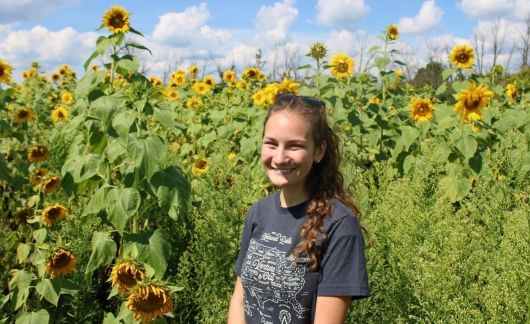 High school student smiling in sunflower field