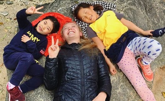 Teacher and students laying on the ground smiling