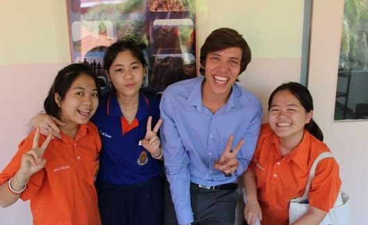 Teach Abroad Teacher and students smiling together against wall