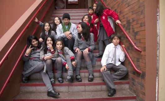 Teach in Chile participant sitting on the steps with Chilean students at school