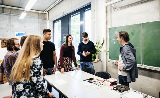 Teacher and students talking around a desk in classroom