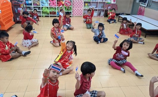 Thai kids in class holding up national flags