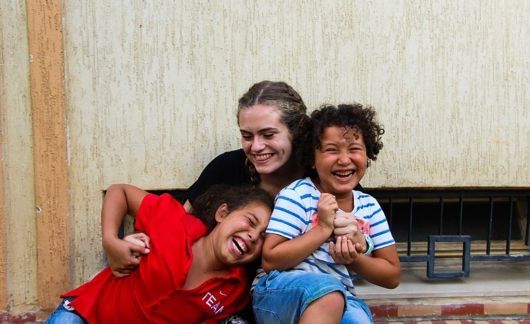 Young woman hugging two laughing kids