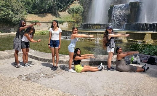 High school students making CIEE with their arms by a waterfall in Rome