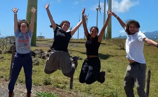 students jump wind turbines monteverde