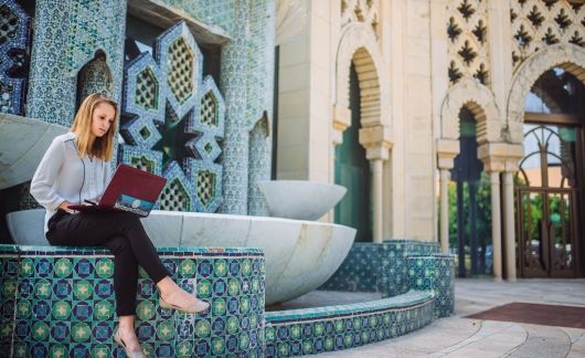 Seville student intern working on laptop by a fountain