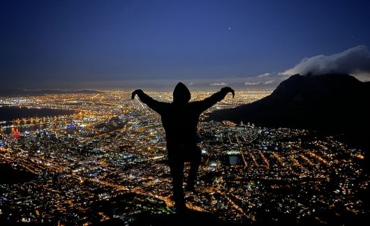 cape town student doing "crane kick" on mountain overlook the city at night