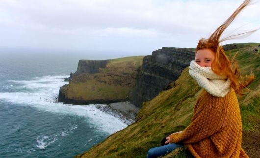 dublin redheaded girl on cliffs with her hair blowing straight up