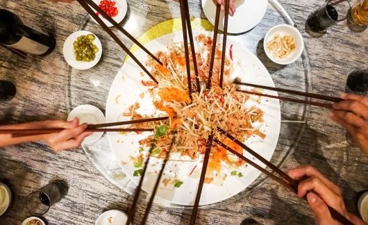 singapore plate of noodles with several hands with chopsticks reaching in