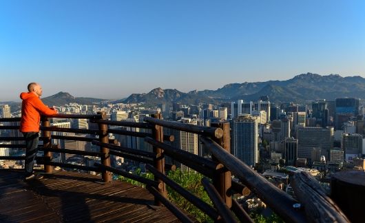 Man looking out at South Korean city from fence