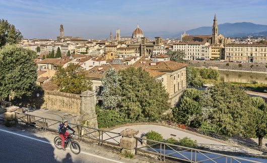 florence biker riding past a rooftop view of the city