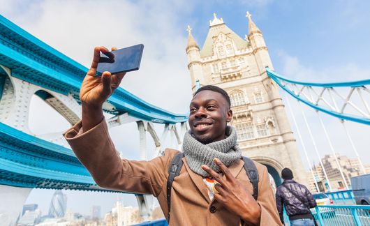 man-taking-selfie-london-tower-bridge-in-background