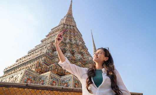 Young woman takes selfie at Wat Pho temple in Bangkok, Thailand