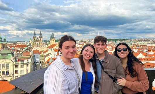 prague-four-students-posing-skyline-background