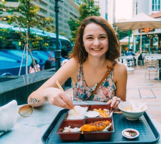 Singapore girl eating outside from a bento box at a cafe table