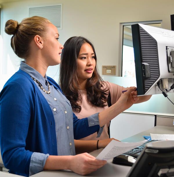intern working with a professional at a computer terminal