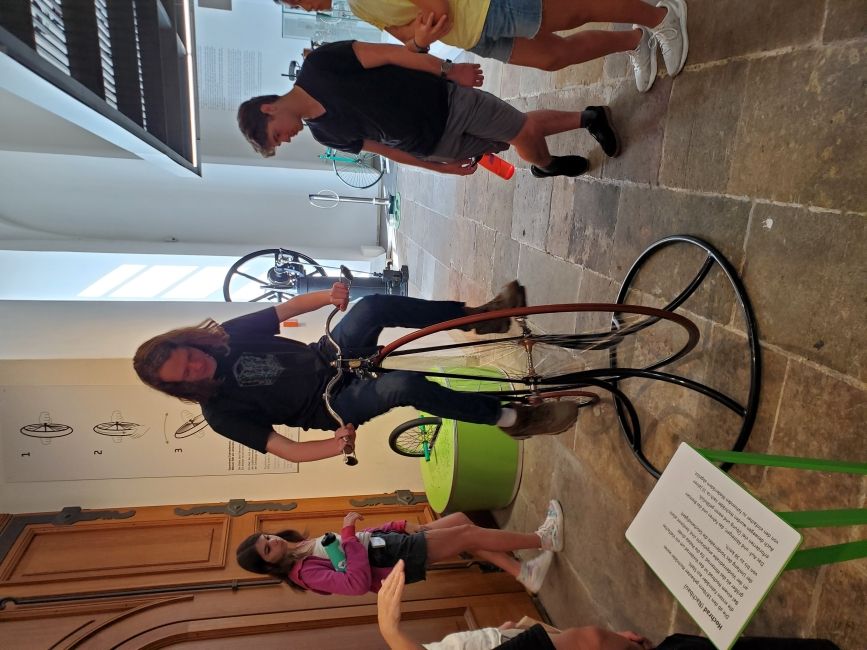 Students climbing onto an old-fashioned bike at the Transport Museum