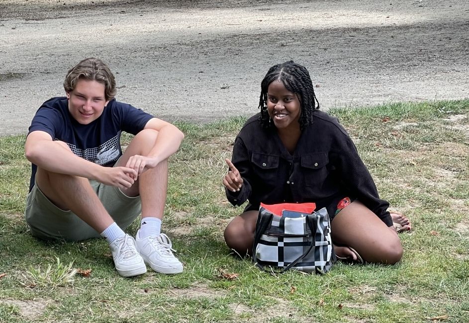 Two participants sit on the grass, smiling