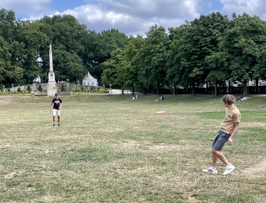Two boys play frisbee in the park