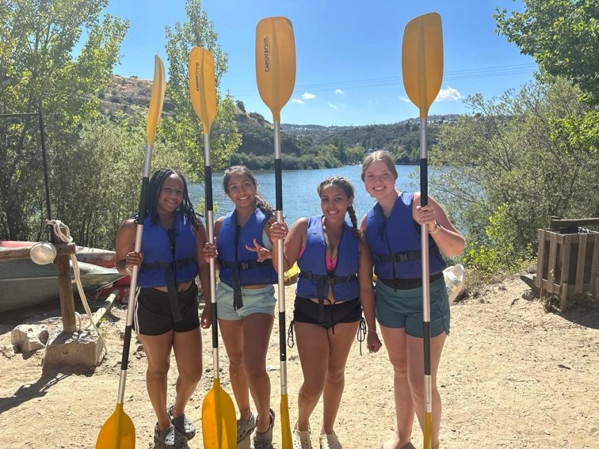 Four students standing with paddles before kayaking
