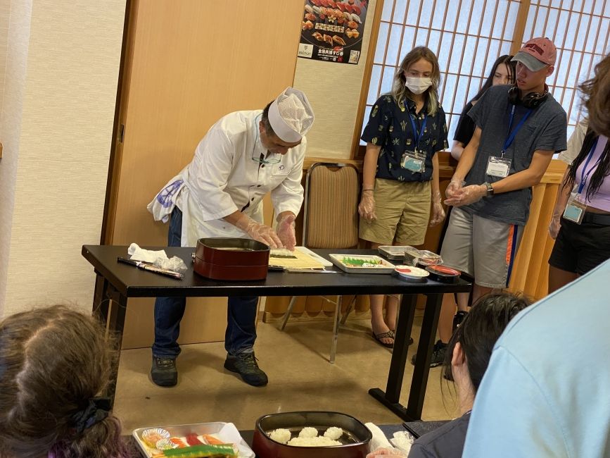 The sushi master shows students how to roll maki-sushi.