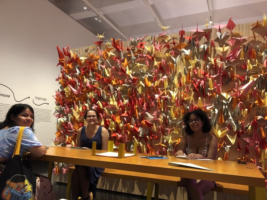 Students working on origami in the Hello Happiness exhibit