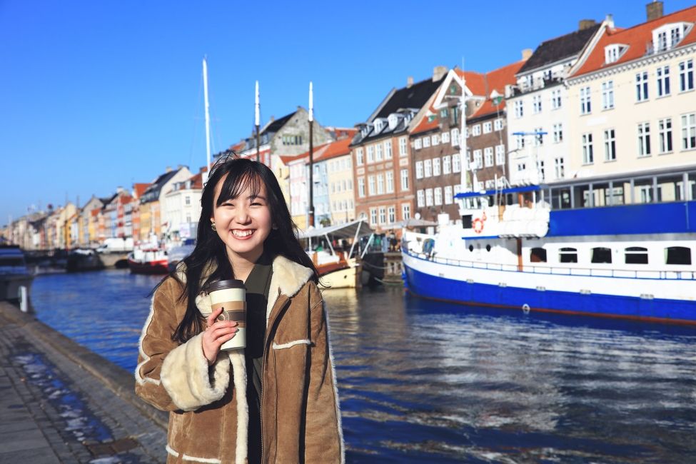 Student posing in front of boats in Copenhagen 