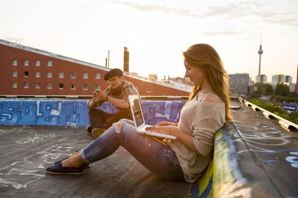 Young woman on laptop on roof in Berlin