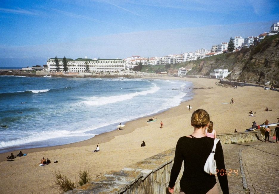a girl walking down a boardwalk toward a beach